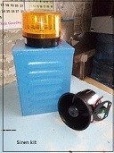 Security alarm siren kit components laid out: outdoor siren horn, flashing strobe light, and protective cover.